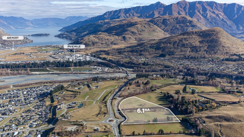 drone image looking at vacant land, houses and the queenstown airport