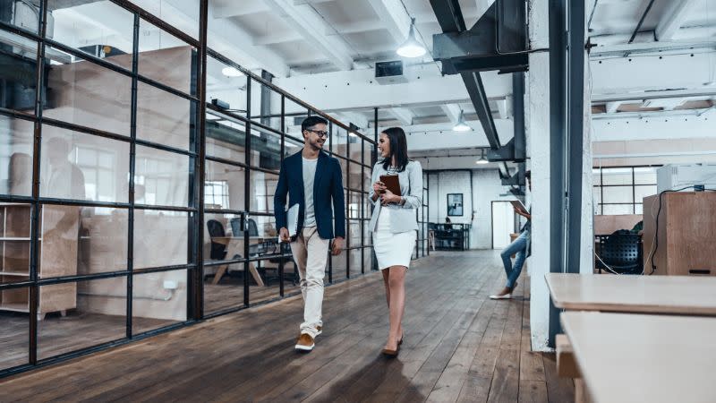 Colleagues walk and talk in a modern office.