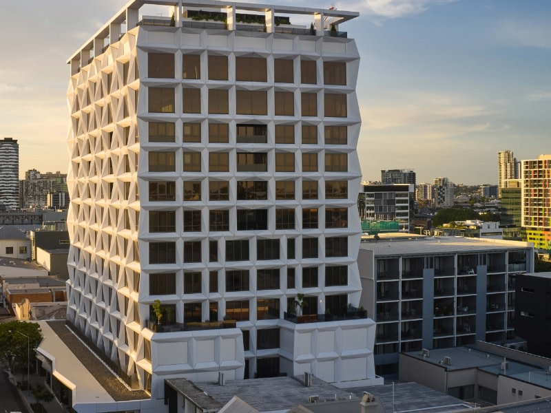 Hotel X in fortitude valley brisbane is a white tower with a geometric facade, this view shows the low rise buildings behind.