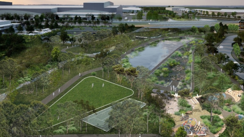 rendering of a large park with a lake, green space and playground next to industrial buildings.