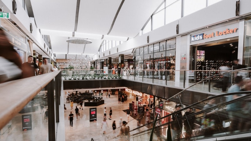 image from inside westfield chermside shopping centre showing a two storey complext with stores and busy escalators