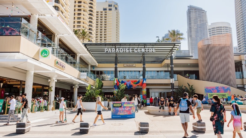 image showing the entrance to a low rise shopping centre with highrises in the background.