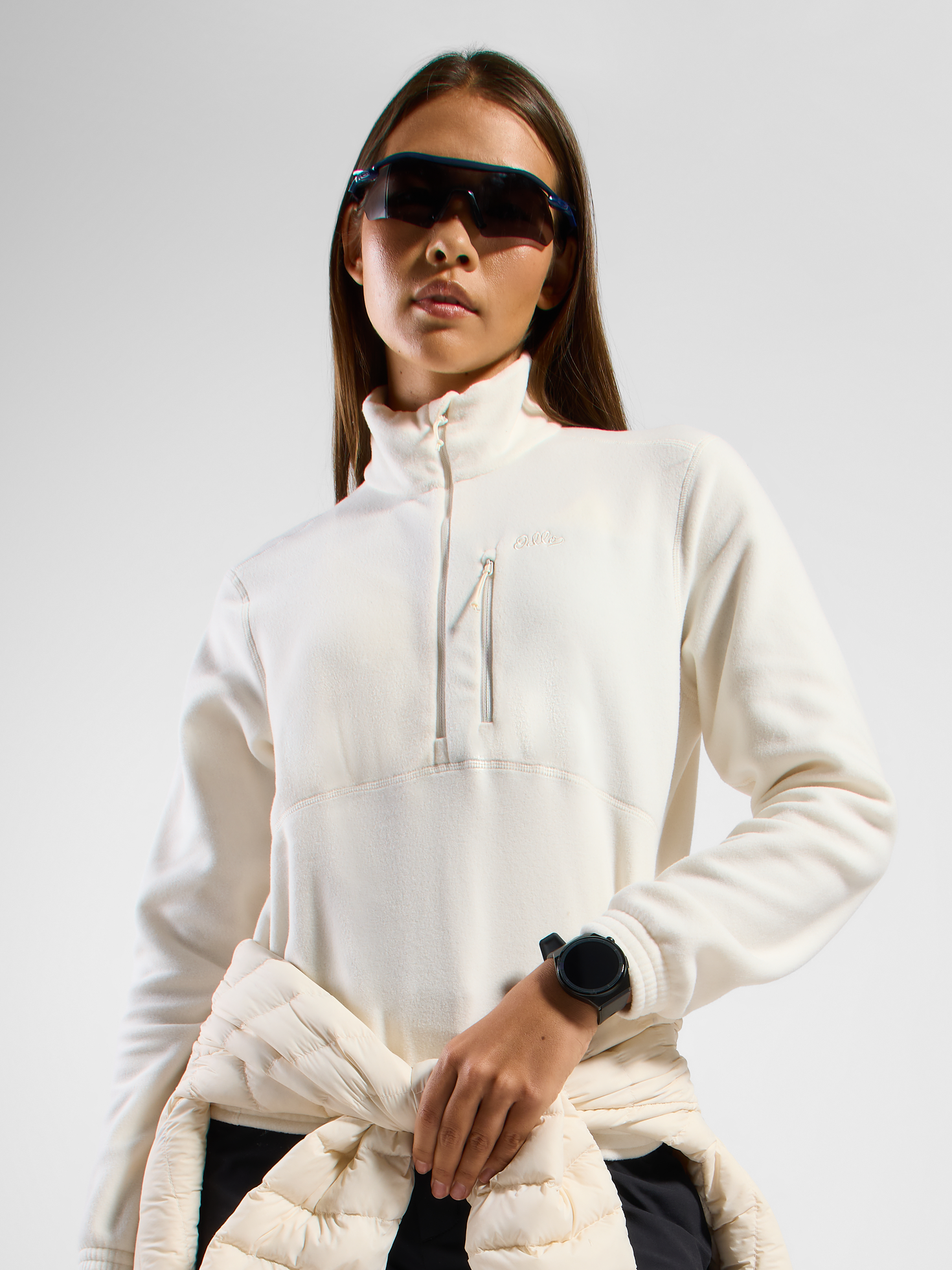Person wearing a white half-zip fleece with a chest pocket, a black smartwatch, and a jacket tied at the waist.