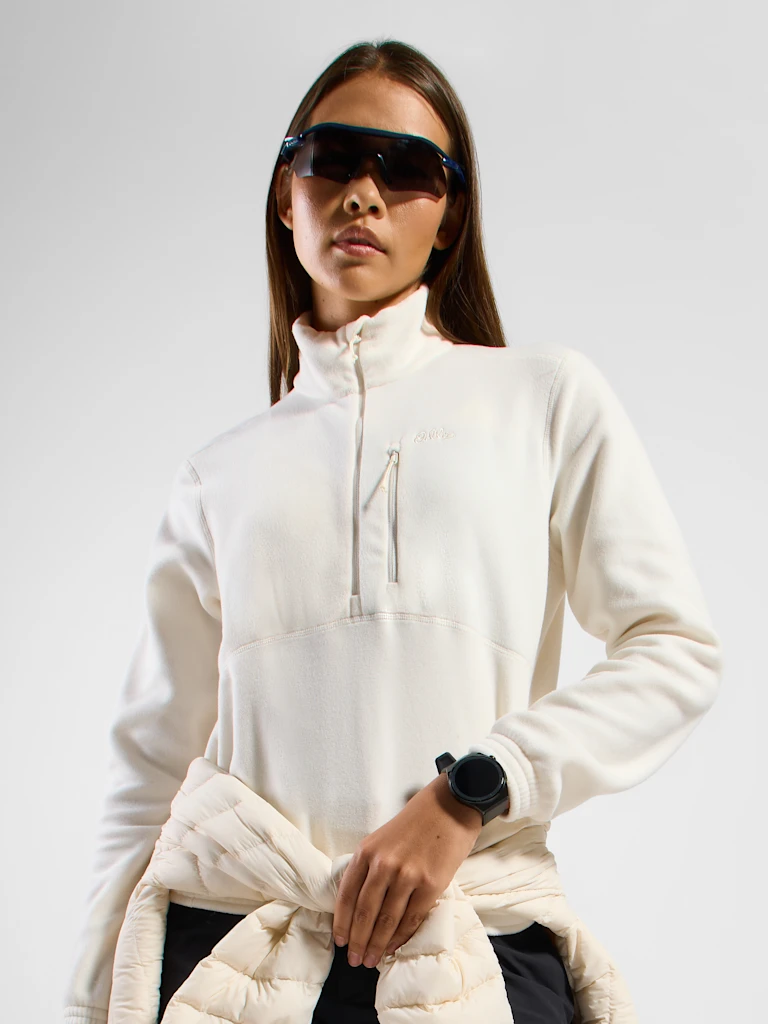 Person wearing a white half-zip fleece with a chest pocket, a black smartwatch, and a jacket tied at the waist.