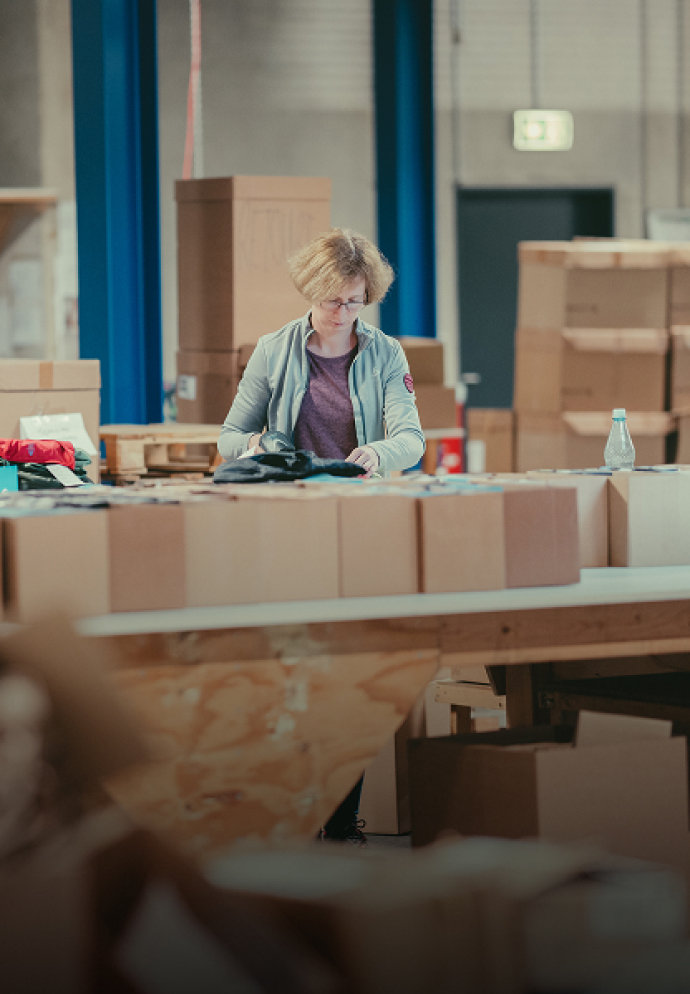 Mitarbeiterin sortiert Artikel in einem Lager – ein Teil unseres Engagements für faire Arbeitsbedingungen.