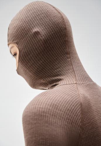 Profile of a person wearing a brown, ribbed knit seamless performance wool base layer covering their head and neck against a light grey background.