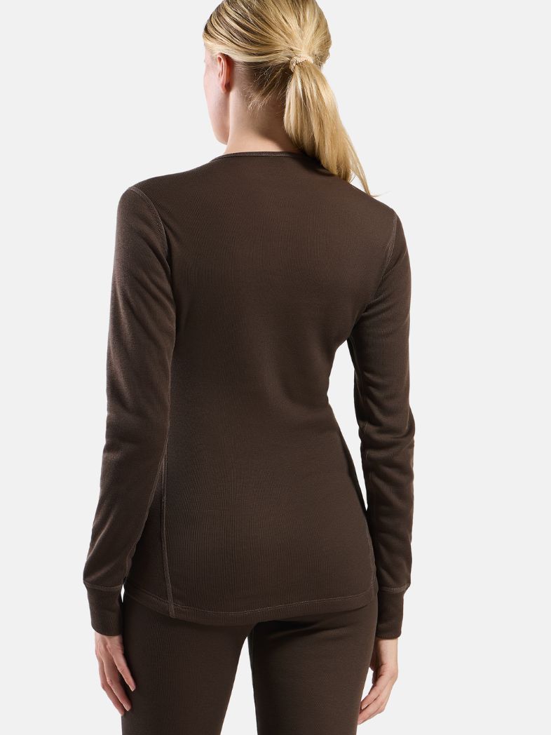 Blonde woman facing forward wearing a light pink, long-sleeved ribbed thermal top against a plain white background.