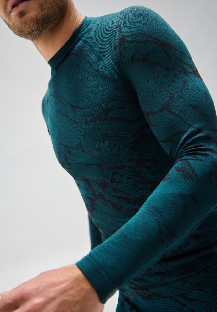 Man in a tight long-sleeved blackcomb base layer with a black marble pattern and ribbed shoulders, posing in motion.