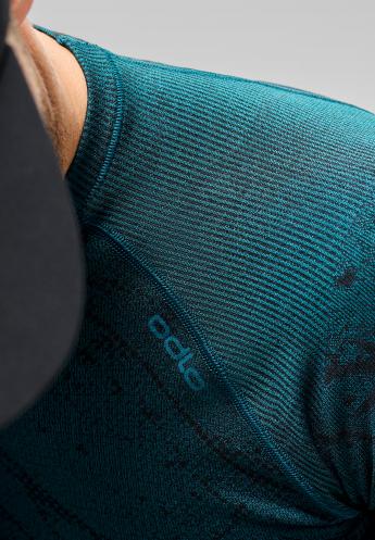 Close-up of a dark teal, ribbed base layer on a men's shoulder, with a black cap partially visible.