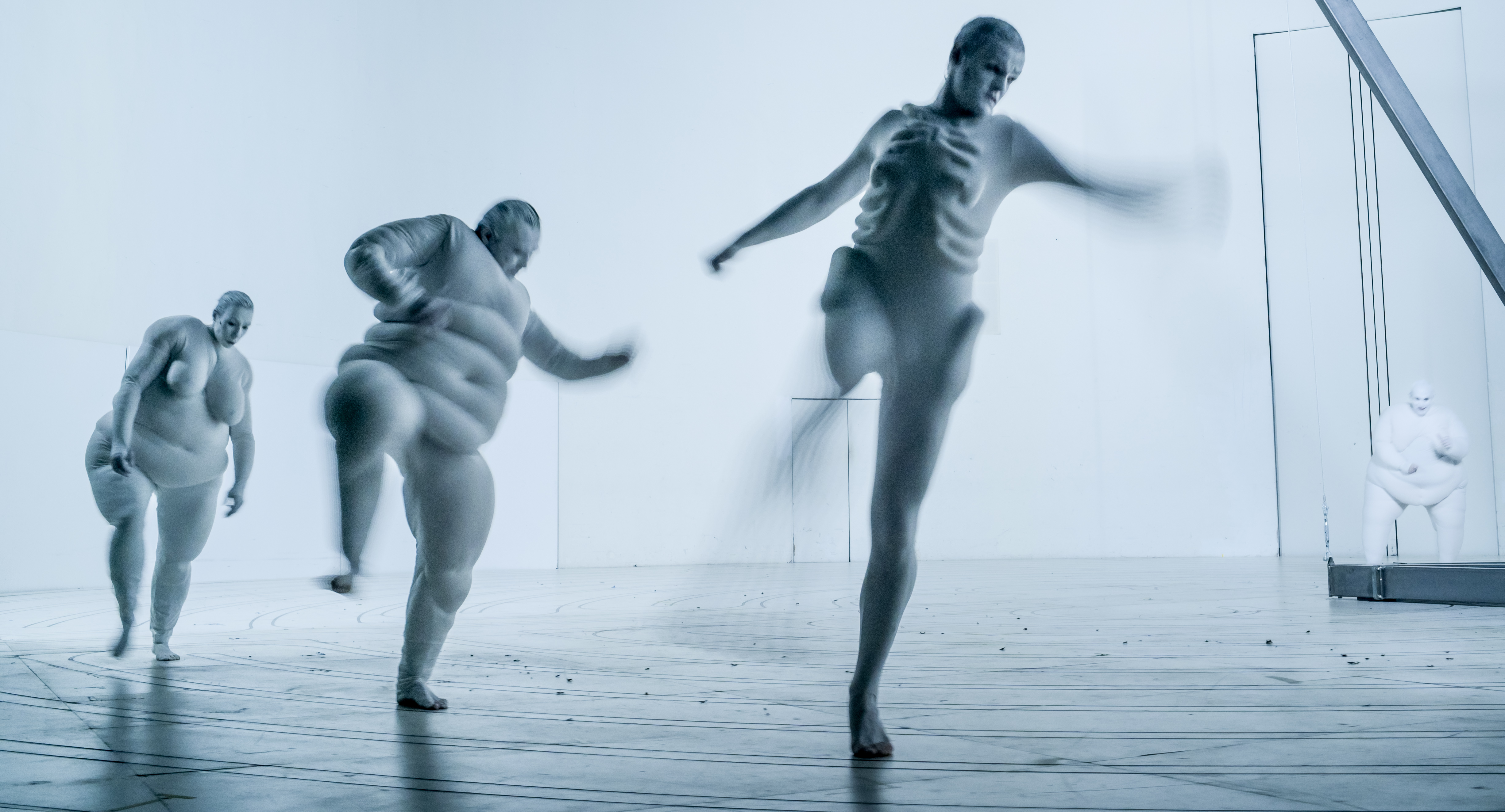 Szene aus der Inszenierung „Der Zauberberg“, die Schauspielerin Linda Pöppe und die Schauspieler Manuel Harder und Niklas Wetzel laufen durch einen weißen Bühnenraum. 