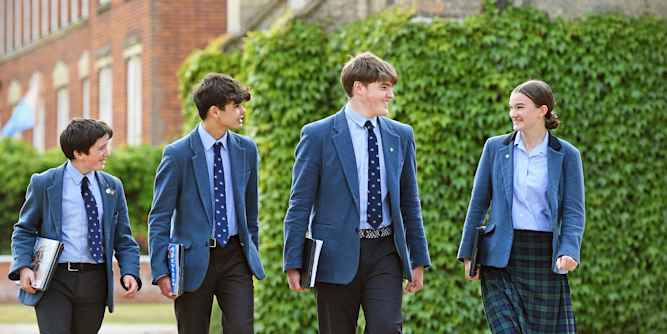 Greshams School - Students in school uniform walking on school grounds to lessons Greshams School - Students in school uniform walking on school grounds to lessons