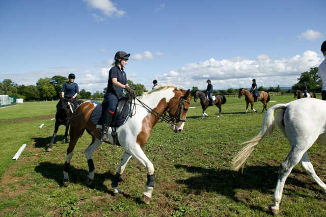 Die Schüler reiten auf einem Reitplatz der Schule auf eigenen Pferden und auf Pferden der Schule