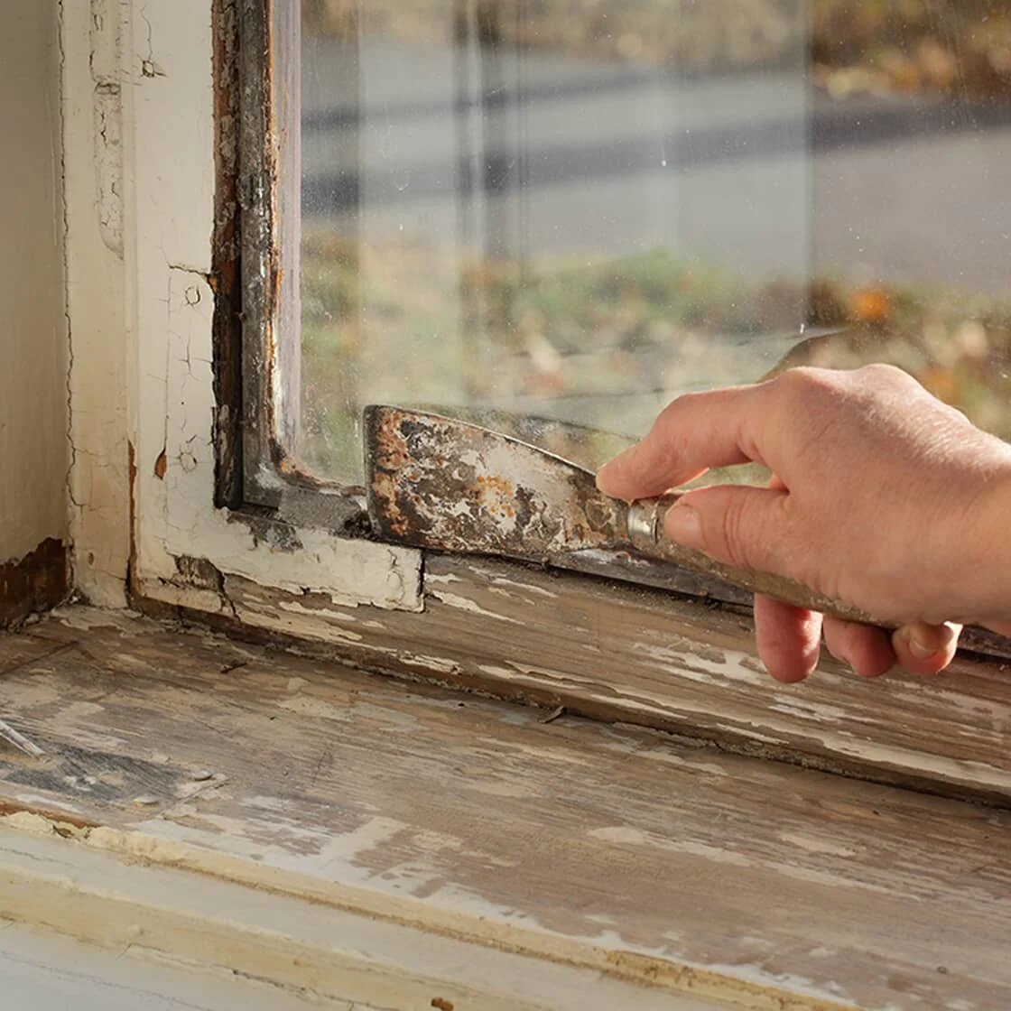 Person scrapping off old wood