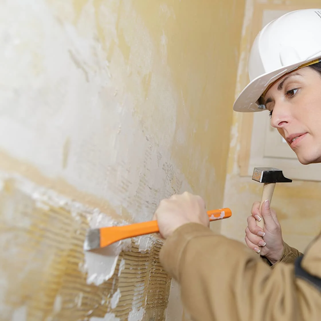 Person scrapping plaster walls