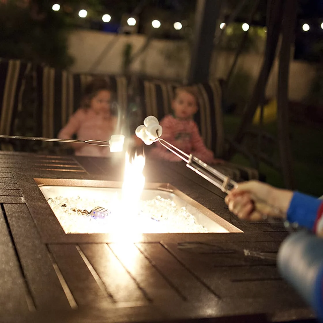 Family outside roasting marshmallows on an outdoor fire table