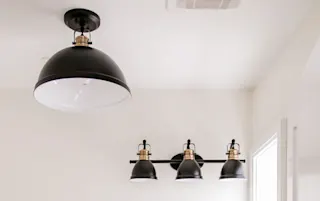Image d’un éclairage de plafond et d’appliques murales élégants en noir et laiton.