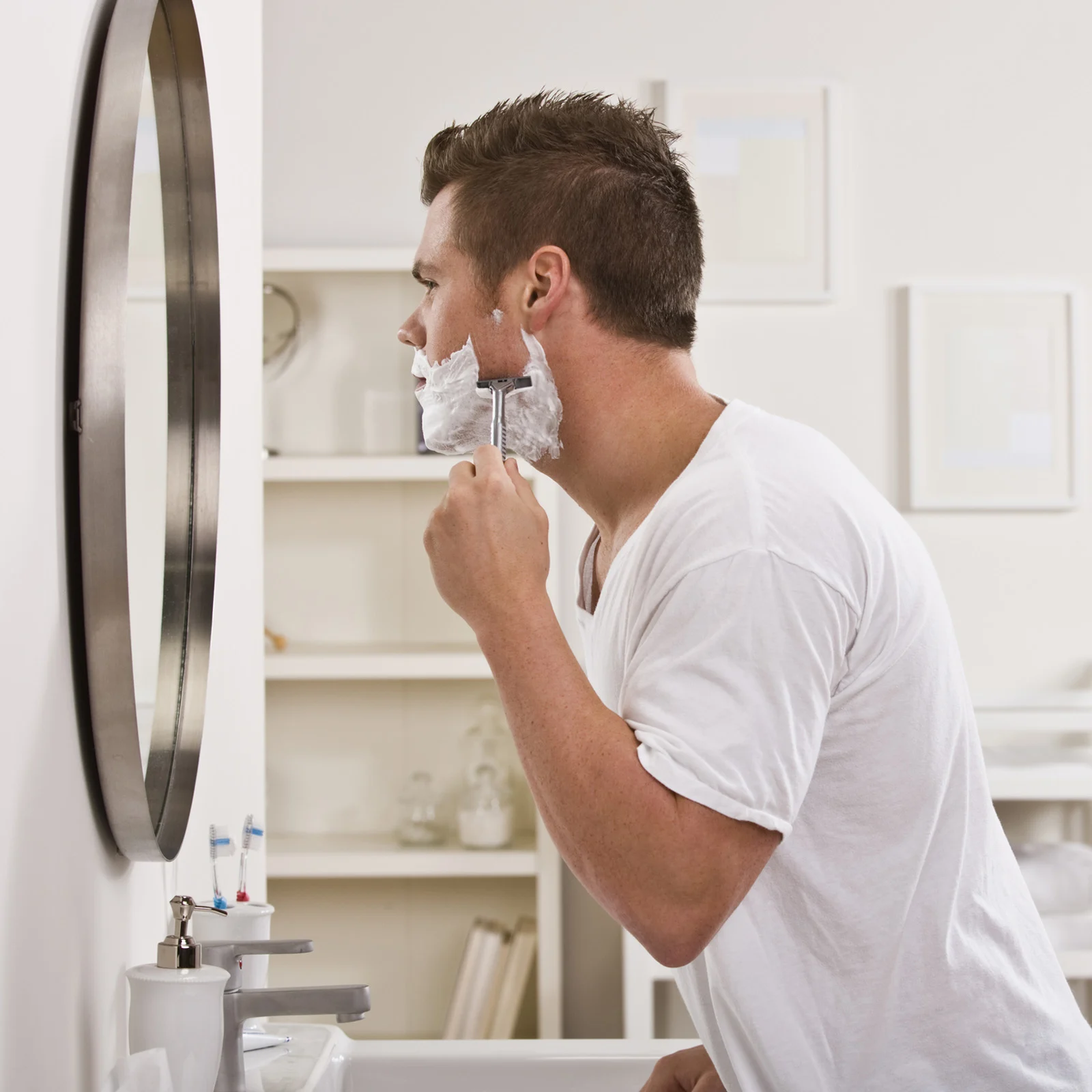 Un homme se rase dans sa salle de bain
