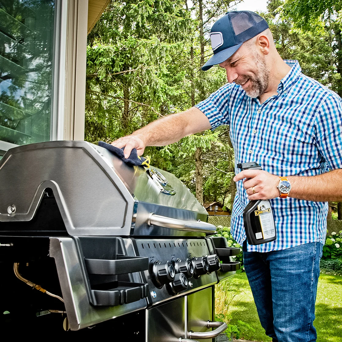Quelqu'un nettoie l'extérieur d'un barbecue.