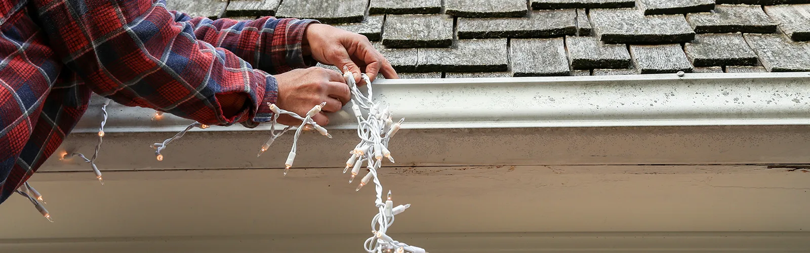 1600x500 Person stringing outdoor Christmas lights