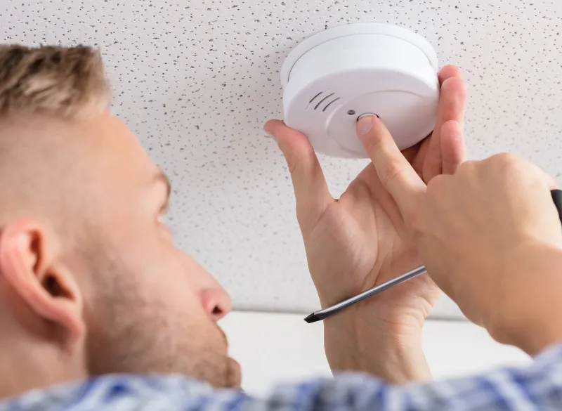 A man installs a smoke detector 