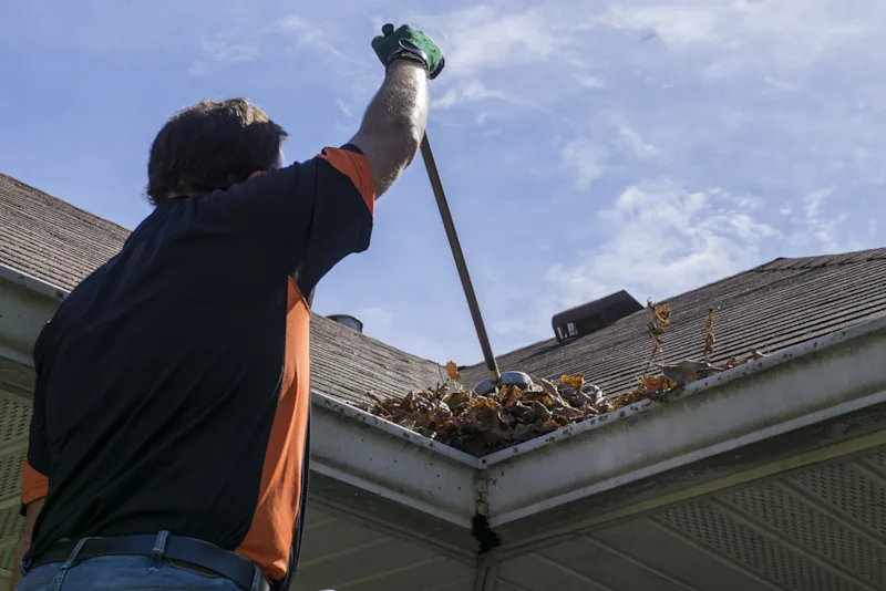 Someone cleaning leaves from their gutters