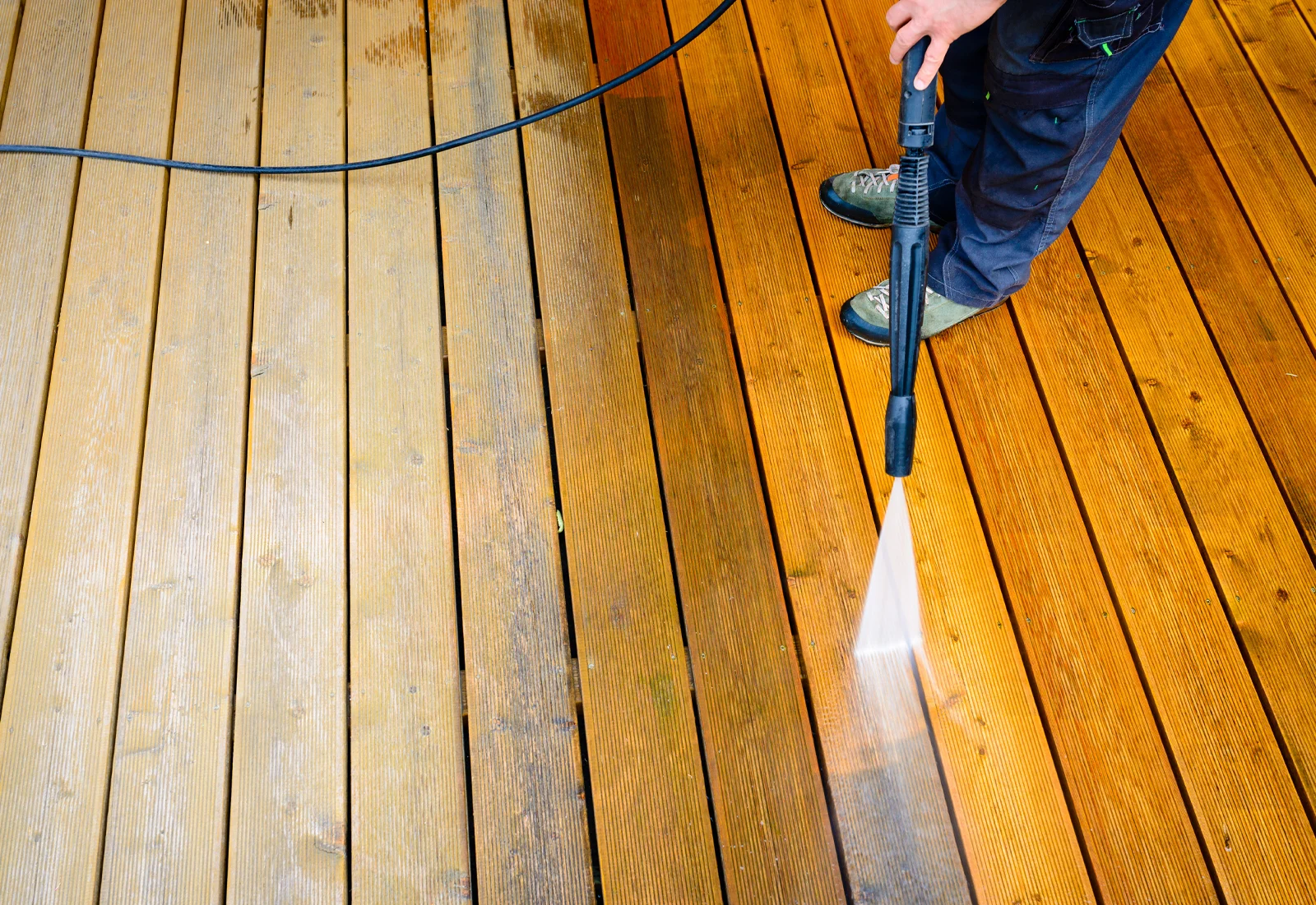 A person power washing a deck