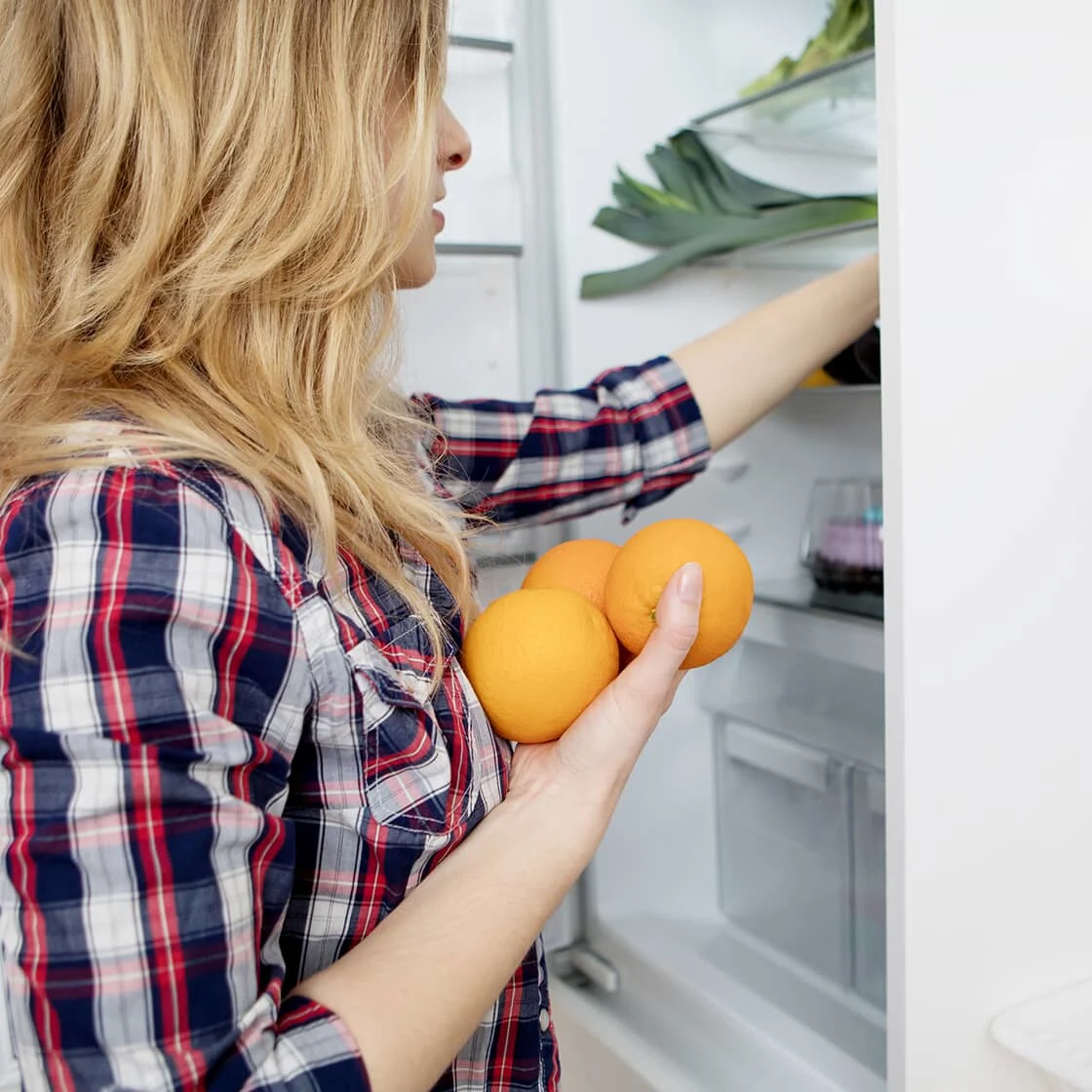 Image of a woman cleaning out, organizing kitchen fridge. 