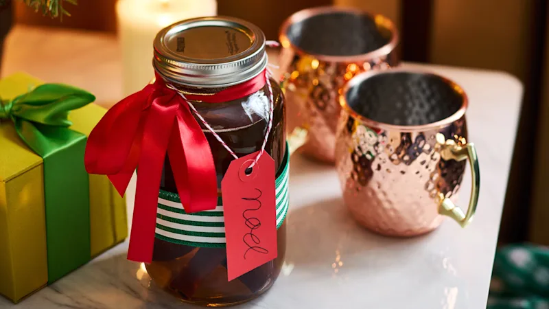 Bocal rempli de mules et de tasses à cocktail de Noël exposé sur une table festive. 