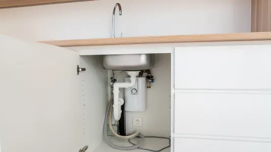 Cabinet door open with water pipes showing