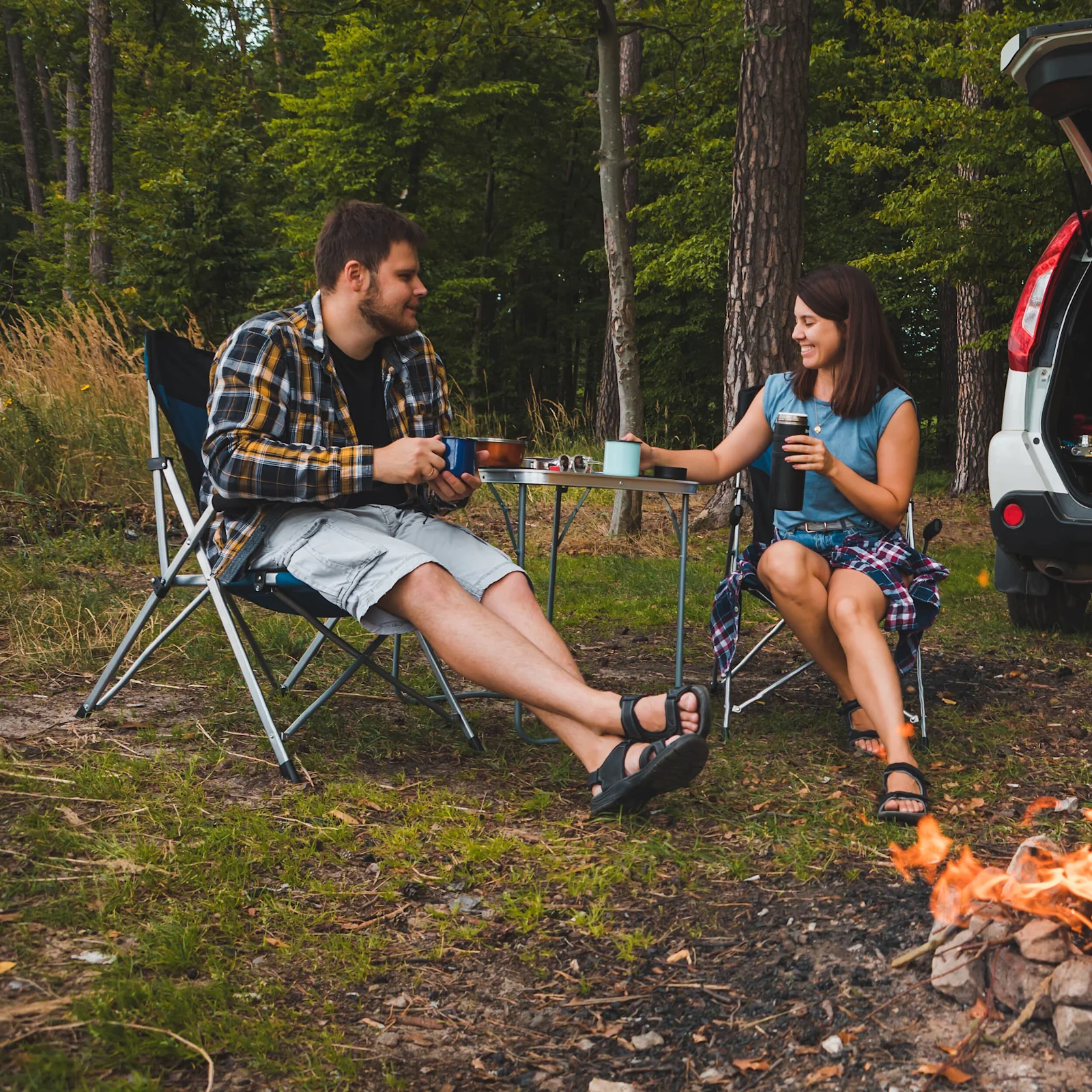 Two people sit in camping chairs.