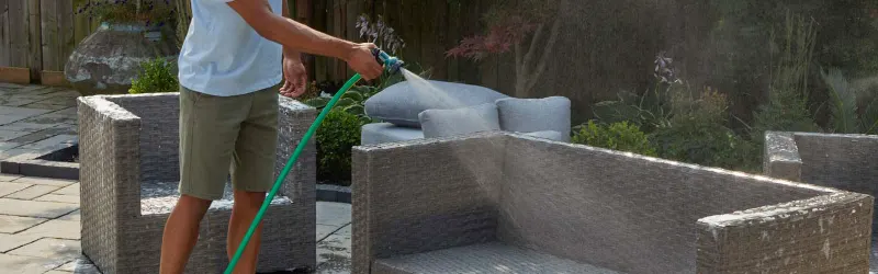 Un homme nettoie un un canapé-terrasse