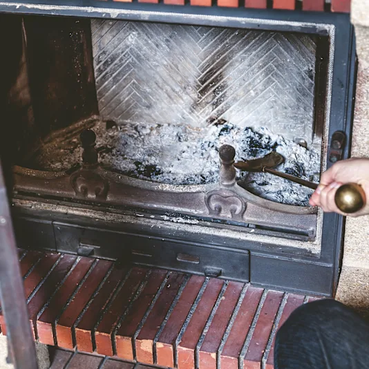 Someone cleans the fireplace.