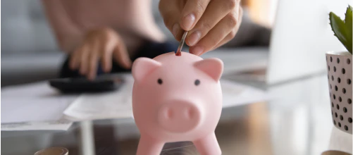 A coin being placed into a piggy bank