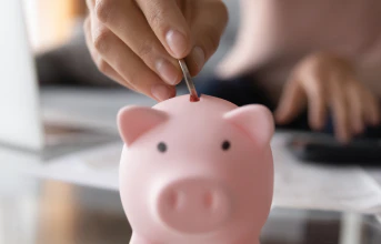 A coin being placed in a piggy bank