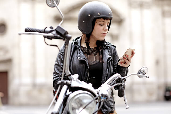 Une femme sur sa moto qui écrit un texto