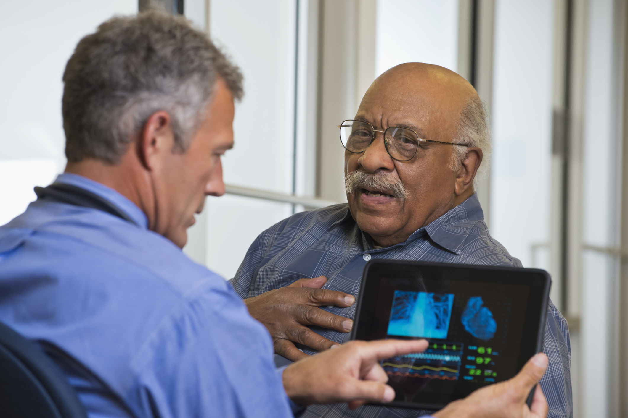 Doctor showing elderly patient his tablet