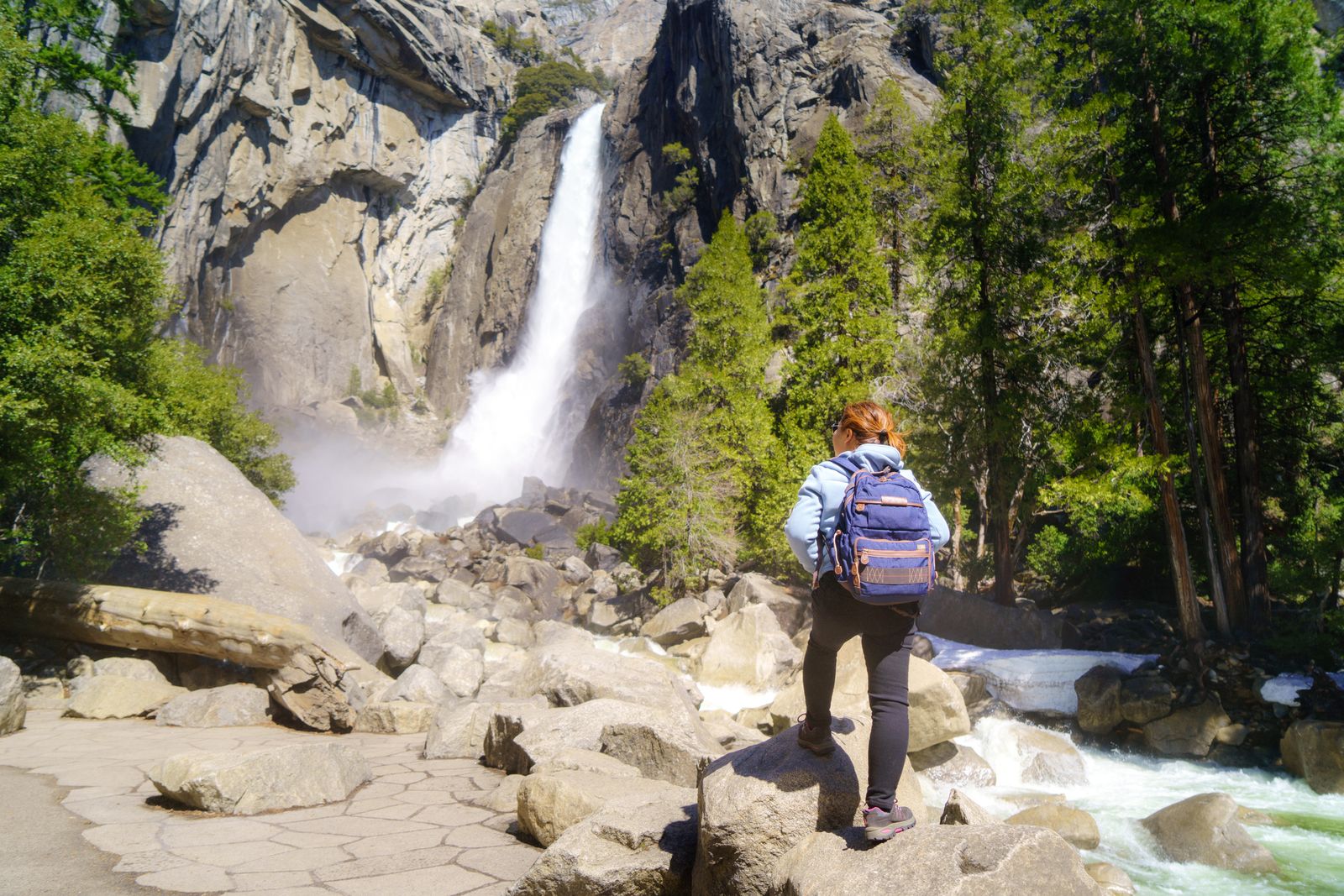 A woman goes hiking near a waterfall