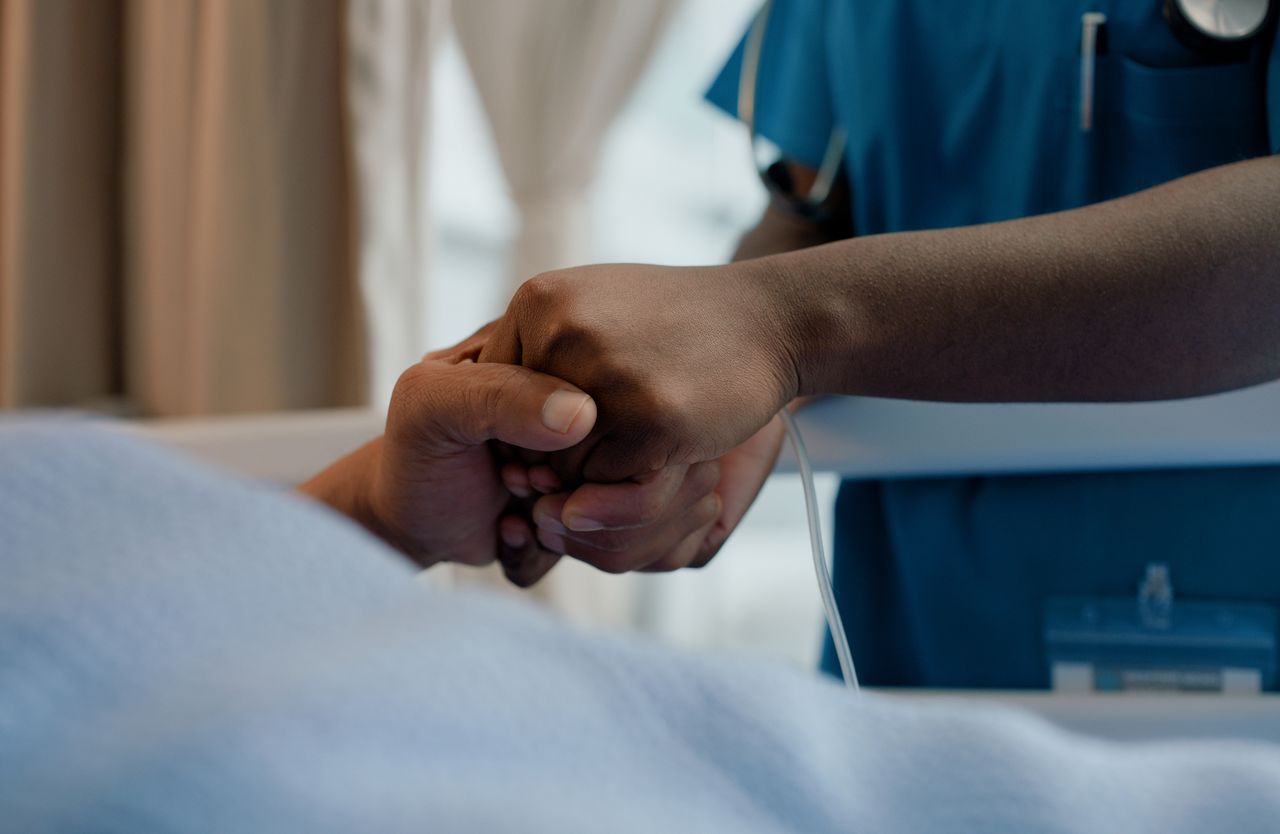 Patient holding nurses hand