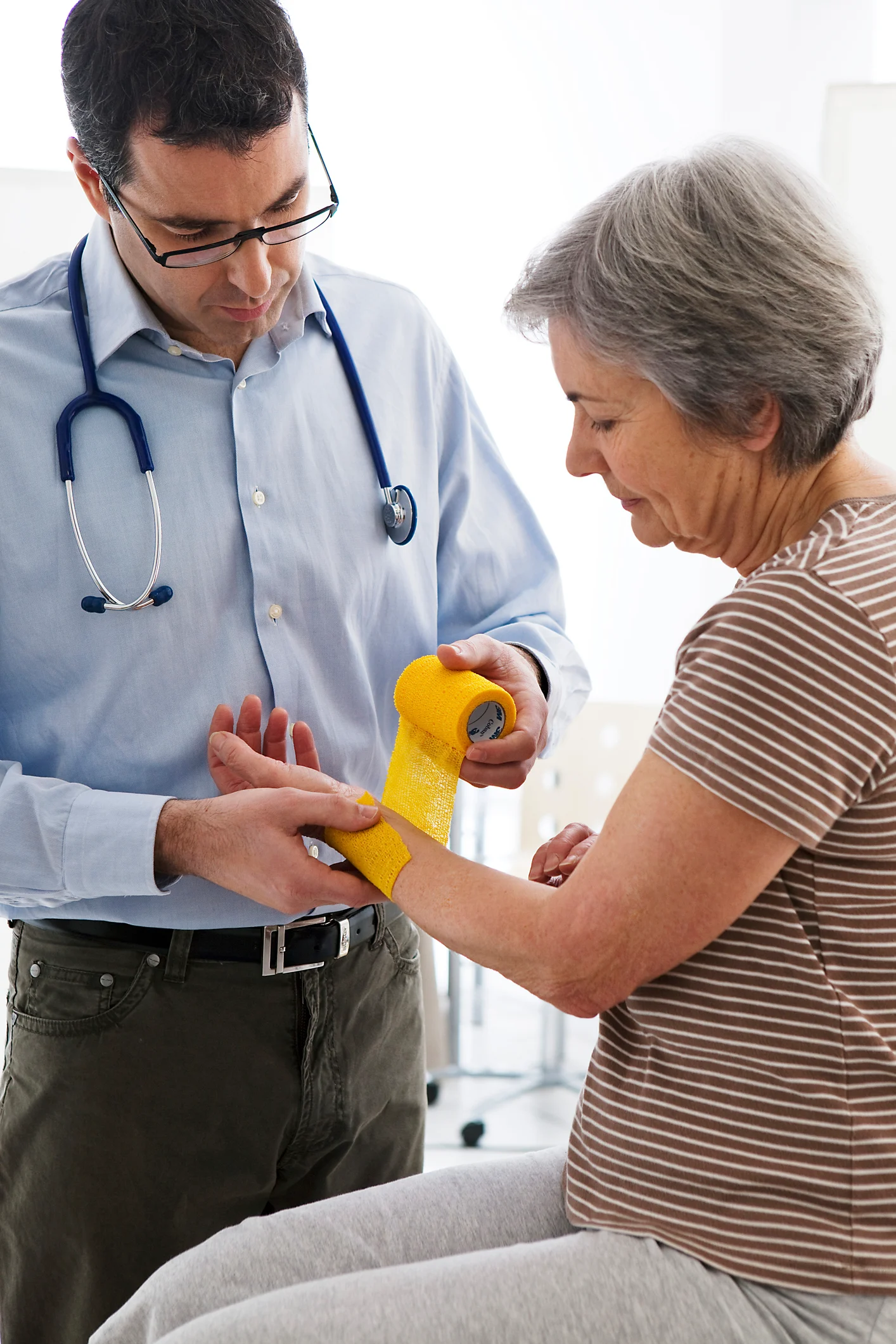 Doctor wrapping the wrist of an older woman