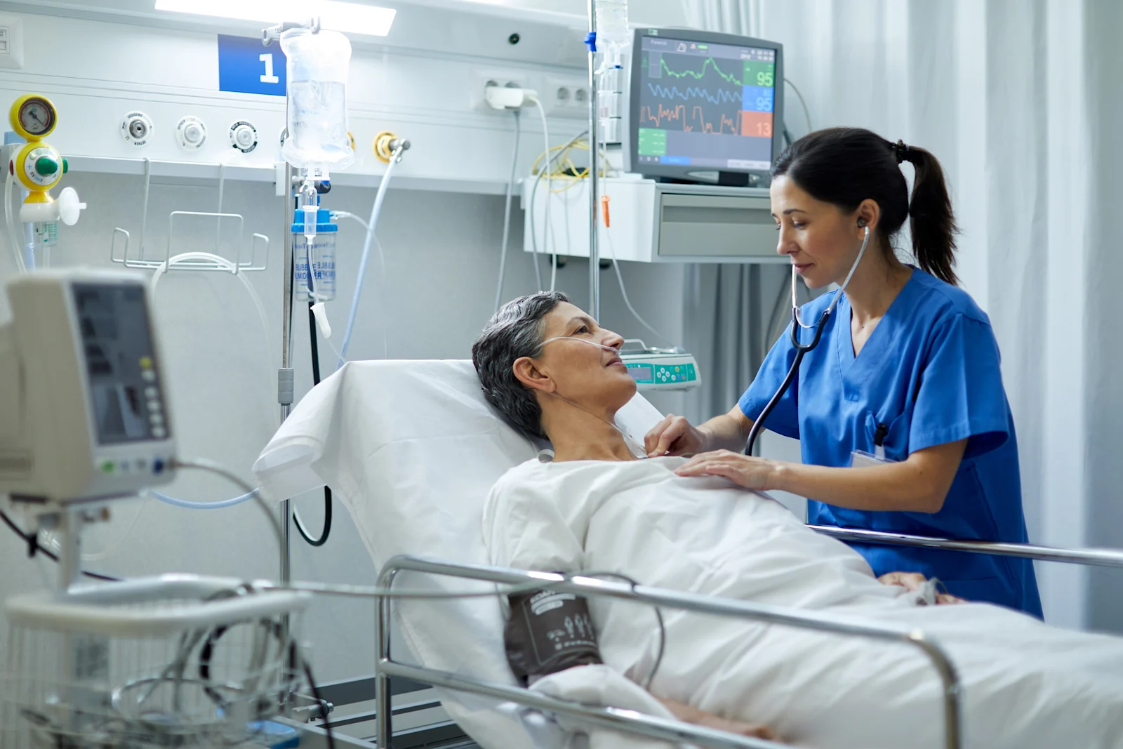 Nurse checking patient in hospital bed