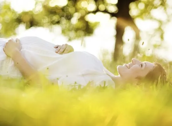 A pregnant woman lays in a field