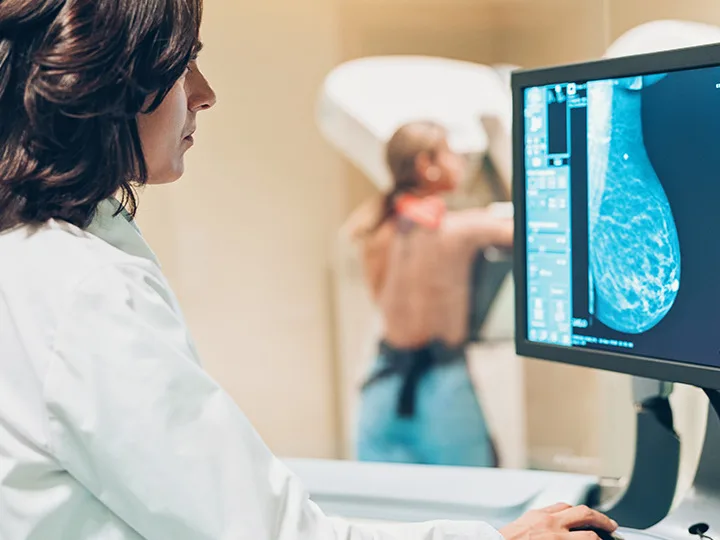 A doctor performs a mammogram on a woman