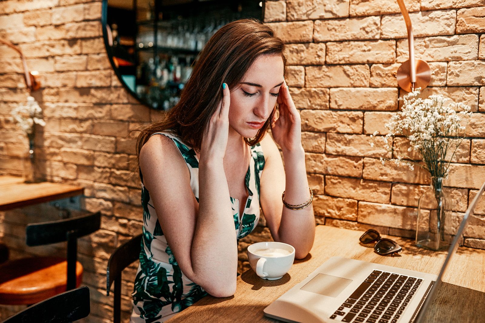 A woman suffers a headache while trying to do work on her computer