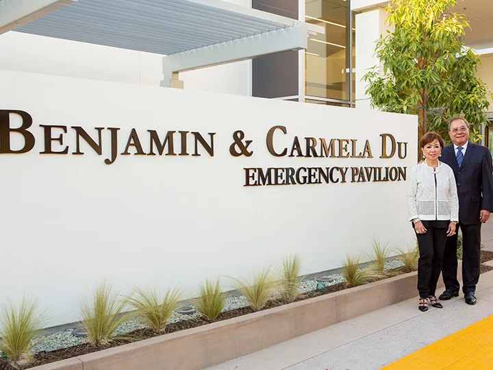 Ben and Carmela Du posing with the signage commemorating their gift