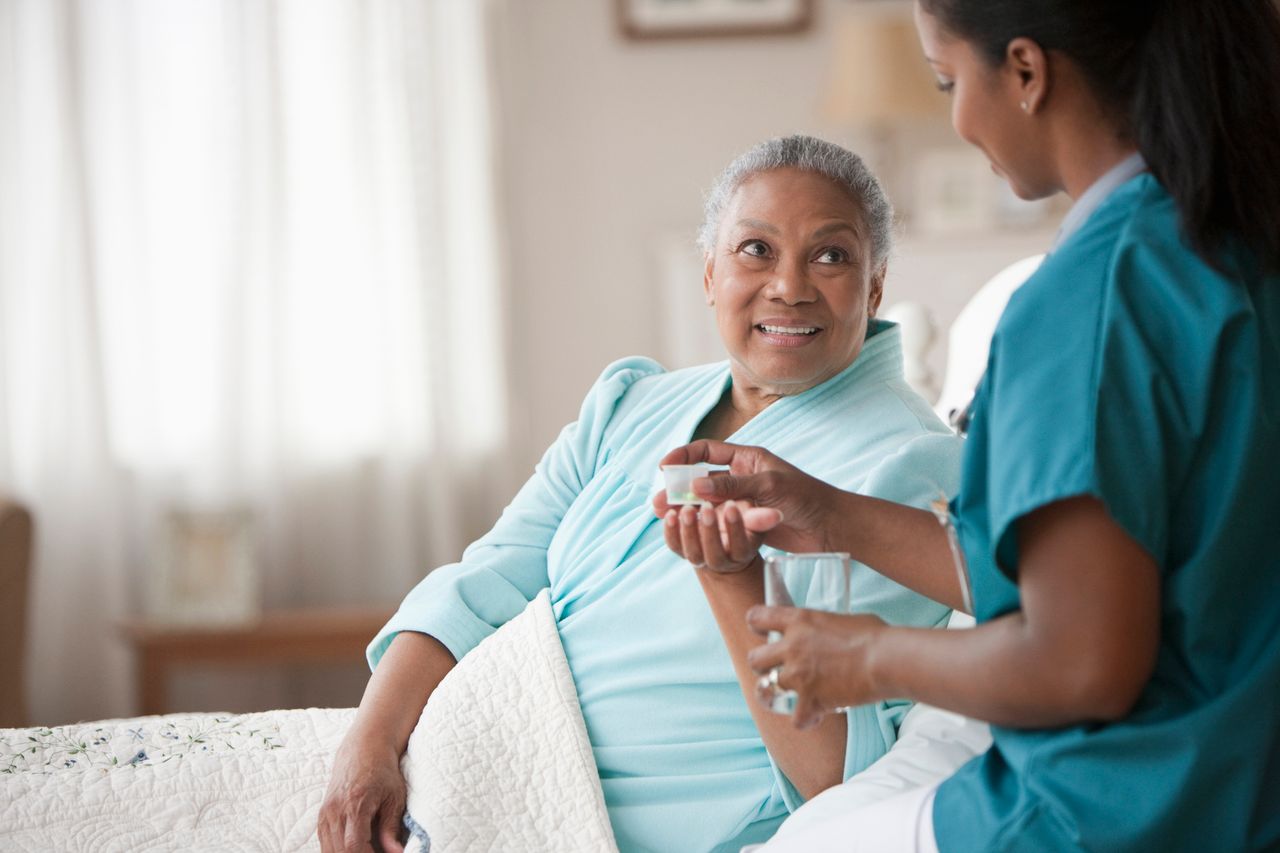 Elderly patient being handed medication by nurse