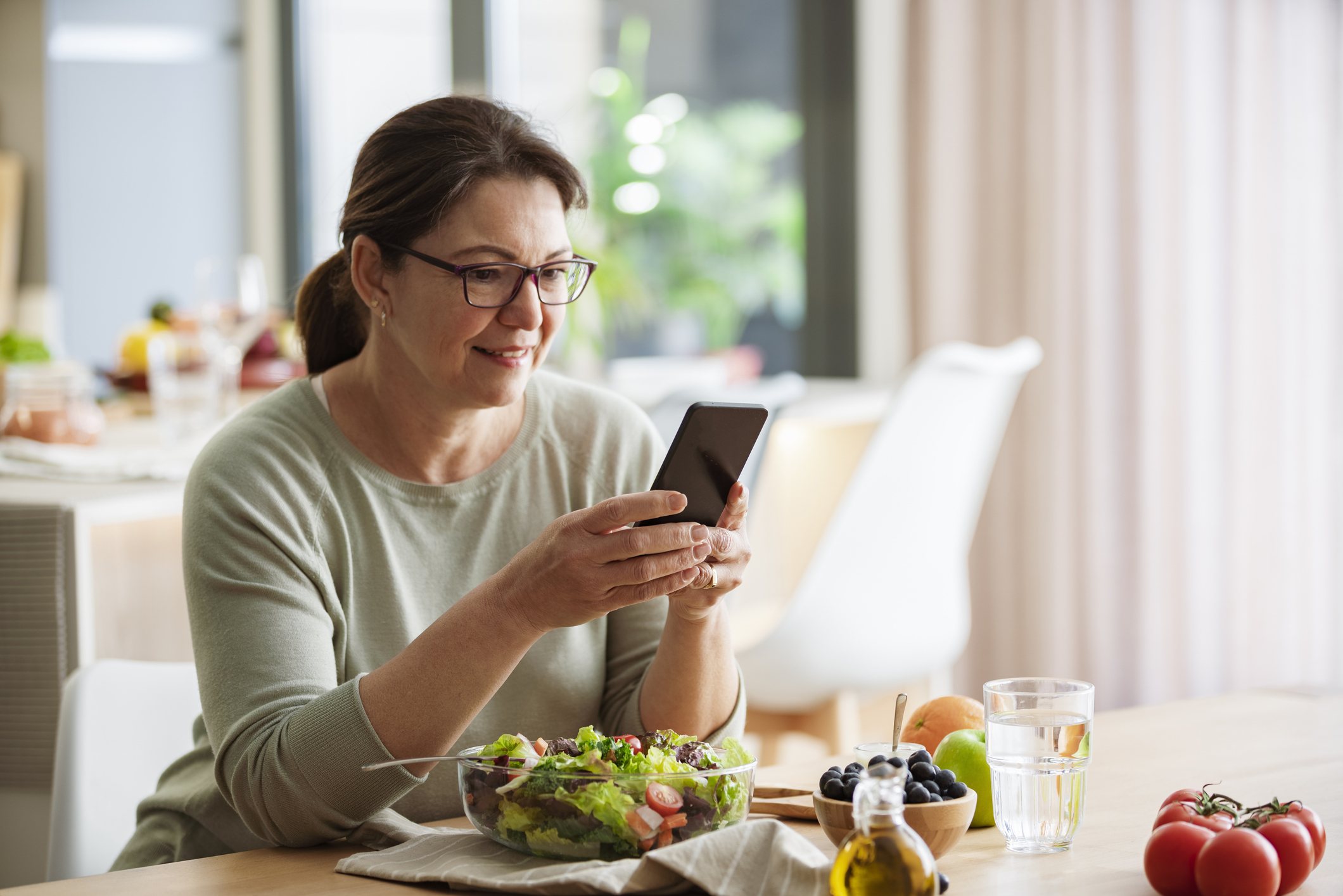 Woman eating healthy lunch with salad and fruit