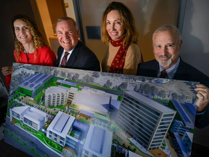 Hoag executive posing with a mockup of the Irvine center