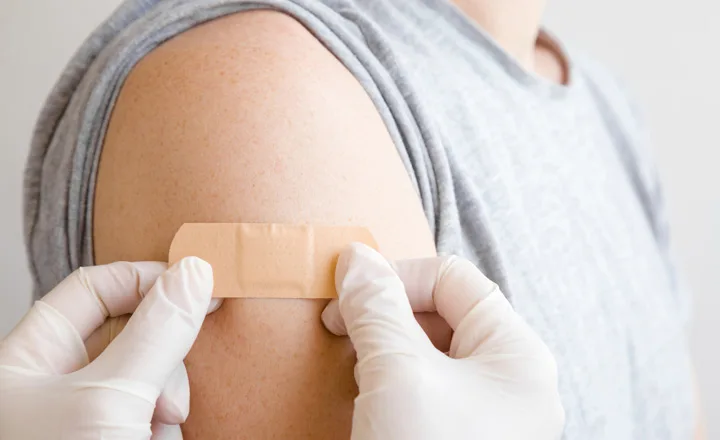 A doctor places a bandage on a flu shot