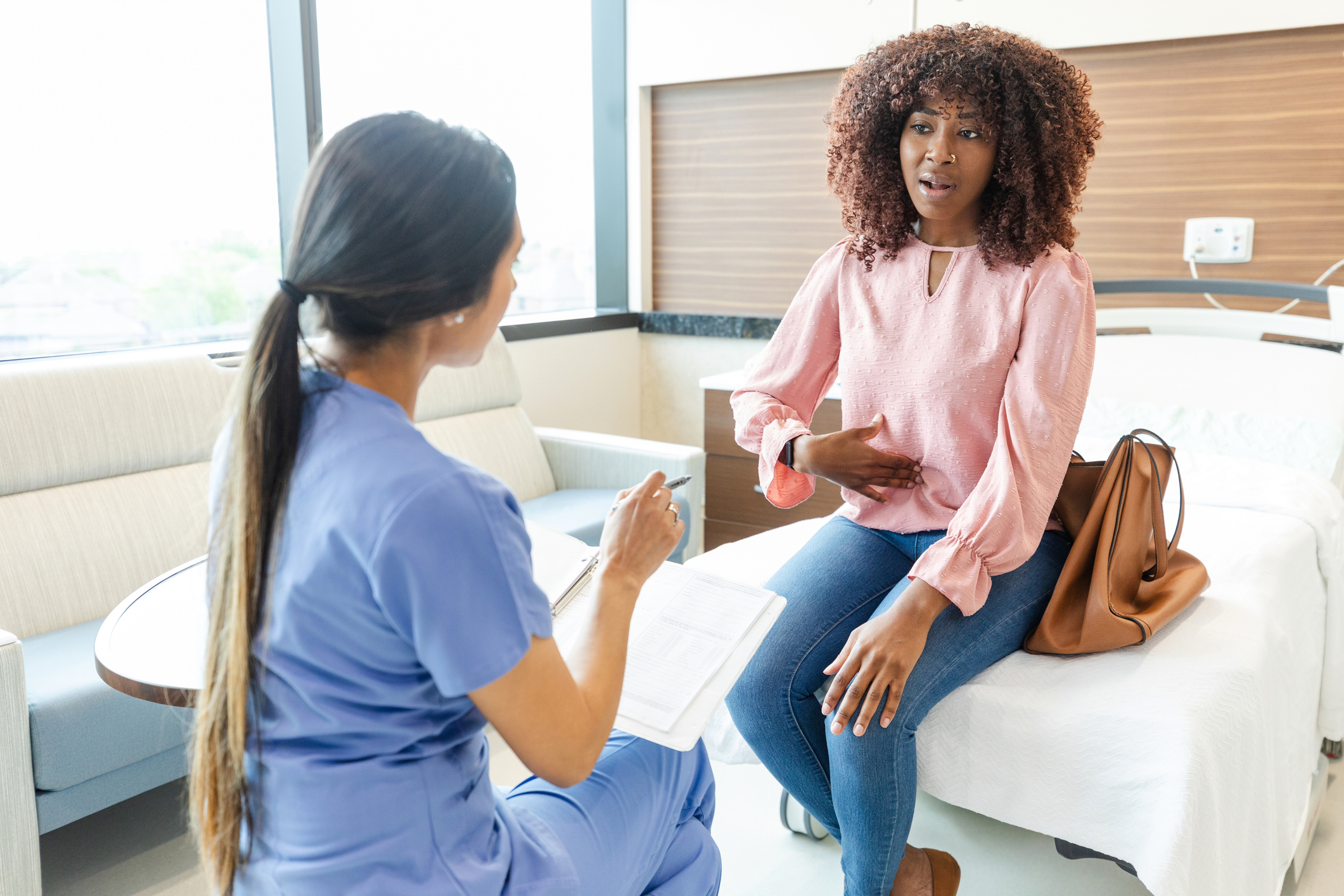 Nurse talking to patient on bed