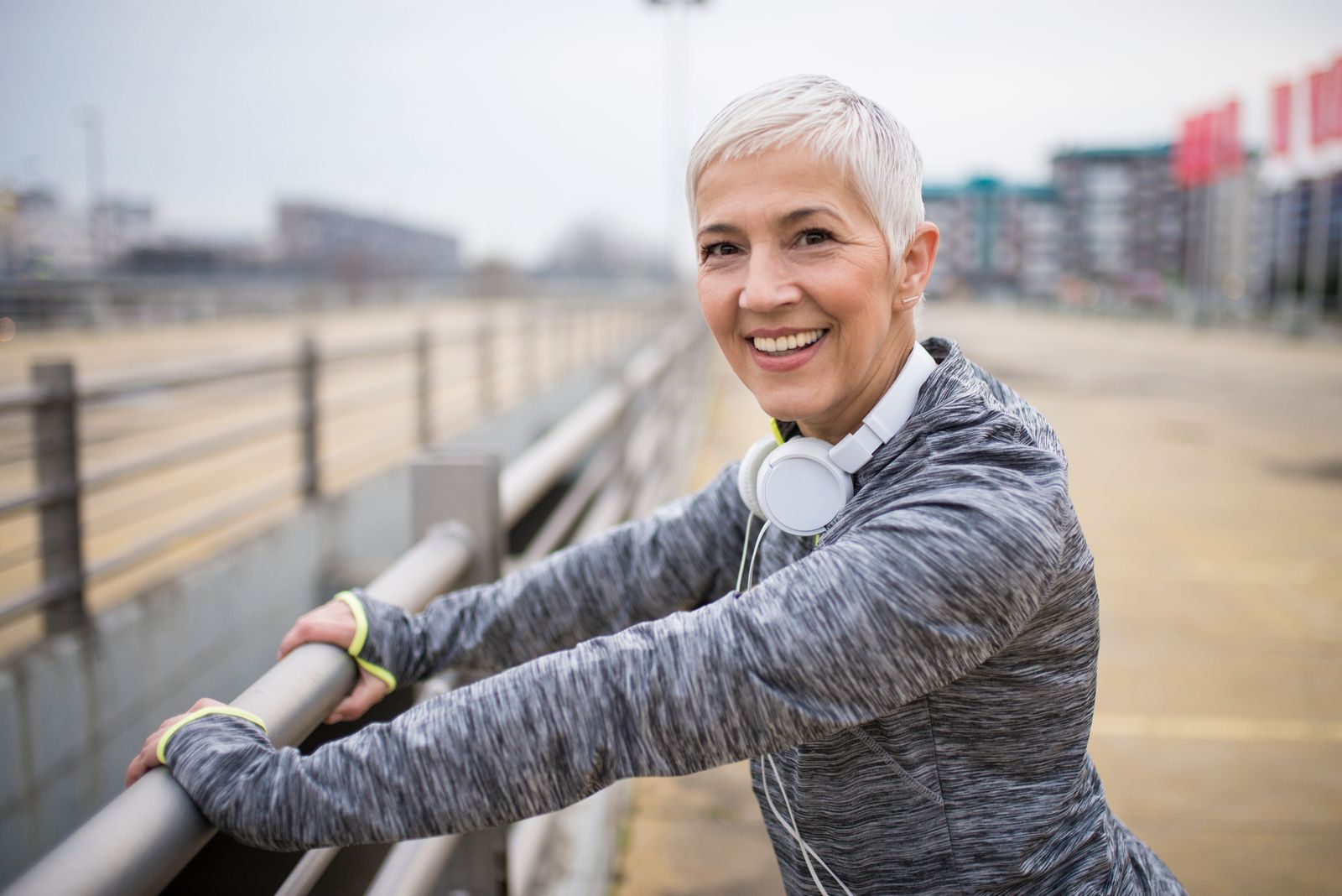 A woman with headphones rests on a fence